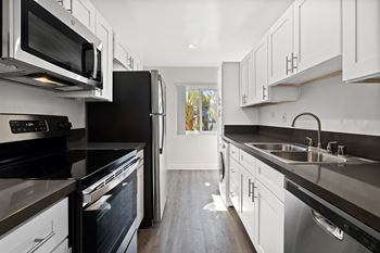 A modern kitchen with black appliances and white cabinets.